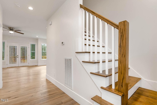 staircase featuring french doors, ceiling fan, and light wood-type flooring