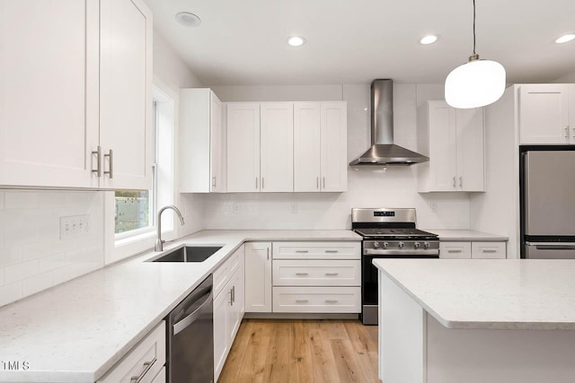 kitchen with appliances with stainless steel finishes, light wood-type flooring, tasteful backsplash, and wall chimney exhaust hood