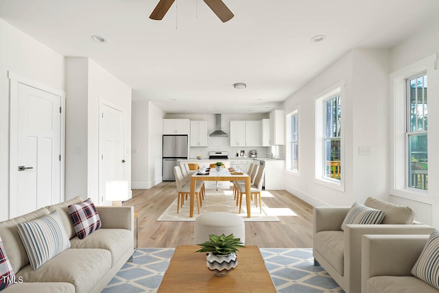 living room featuring ceiling fan, sink, light wood-type flooring, and a healthy amount of sunlight