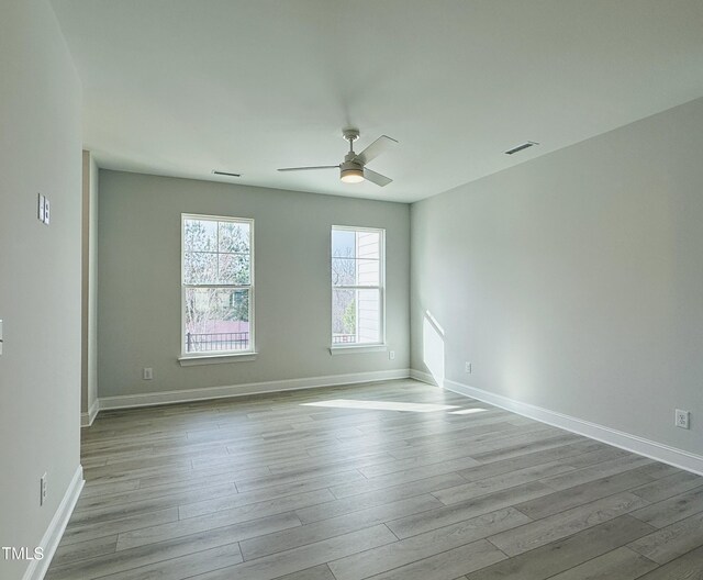 unfurnished room with wood finished floors, visible vents, and a ceiling fan