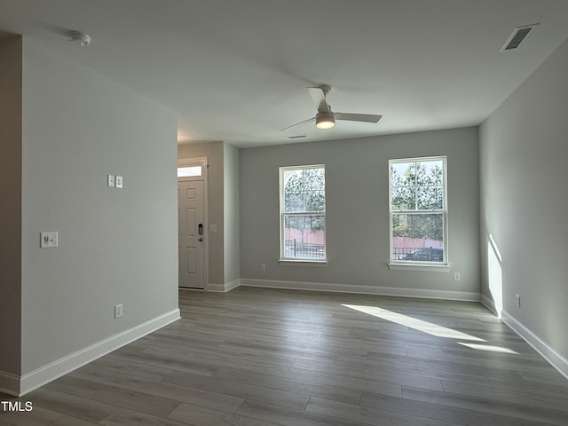 spare room featuring baseboards, visible vents, ceiling fan, and dark wood-type flooring