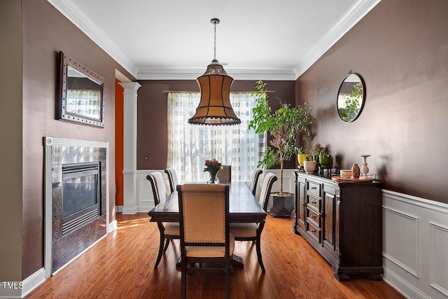 dining room featuring hardwood / wood-style floors, crown molding, and a tile fireplace