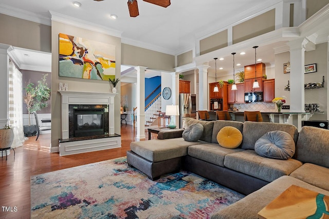 living room with hardwood / wood-style floors, ceiling fan, ornamental molding, and a premium fireplace