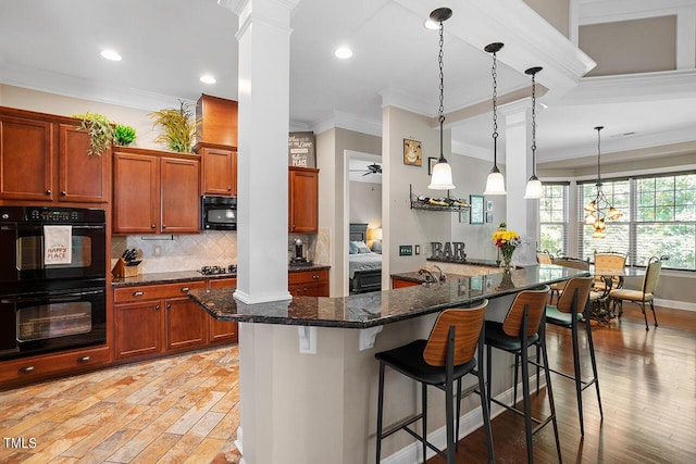 kitchen featuring light wood-type flooring, a breakfast bar area, dark stone countertops, and black appliances