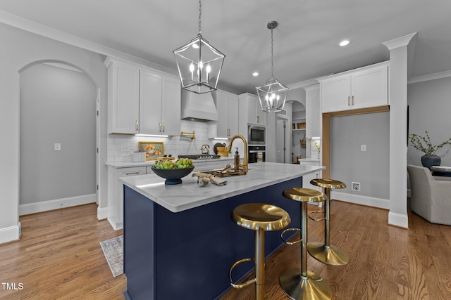 262 Hook Dr Lot 12, Fuquay Varina, NC 27526 - kitchen with arched walkways, stainless steel appliances, custom range hood, white cabinets, and decorative backsplash
