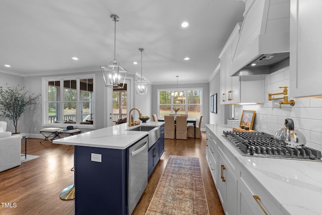 262 Hook Dr Lot 12, Fuquay Varina, NC 27526 - kitchen featuring appliances with stainless steel finishes, wall chimney exhaust hood, blue cabinets, ornamental molding, and dark wood-type flooring