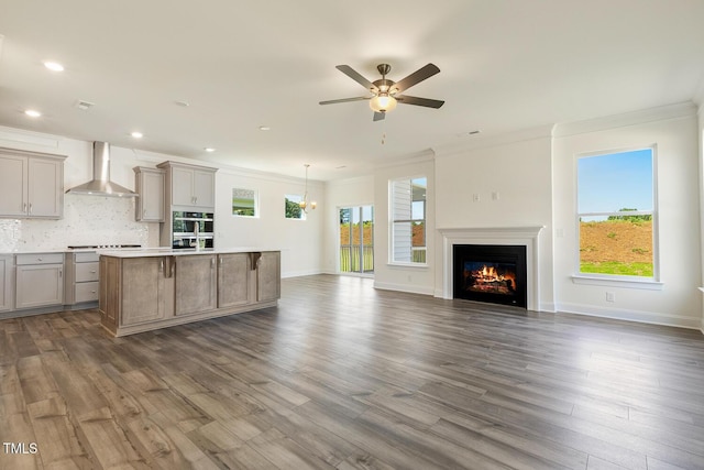 kitchen featuring pendant lighting, wall chimney exhaust hood, a kitchen island, and plenty of natural light