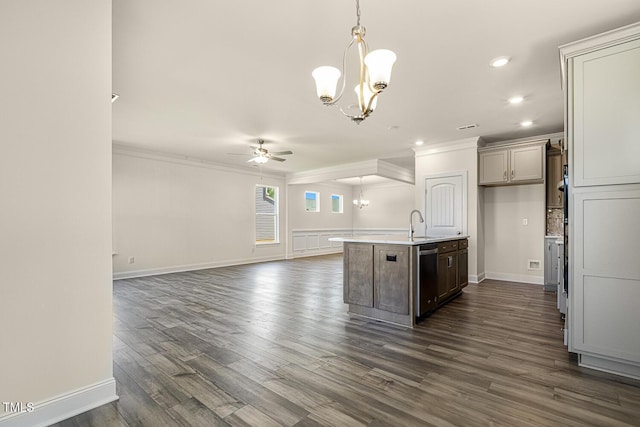 kitchen featuring ceiling fan with notable chandelier, crown molding, dark wood-type flooring, a center island with sink, and hanging light fixtures