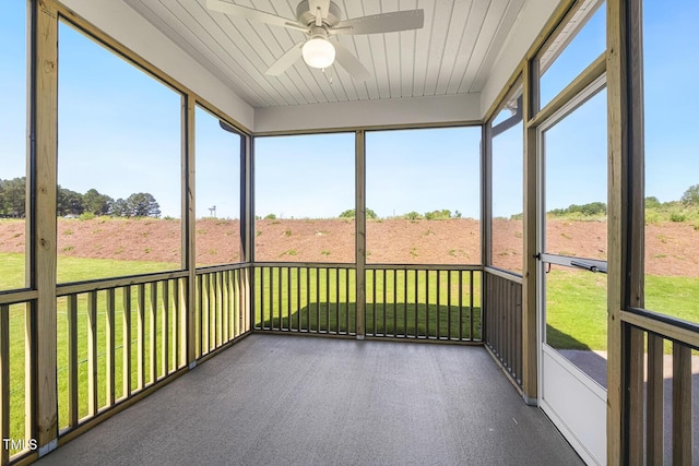 unfurnished sunroom with ceiling fan, wood ceiling, and a rural view