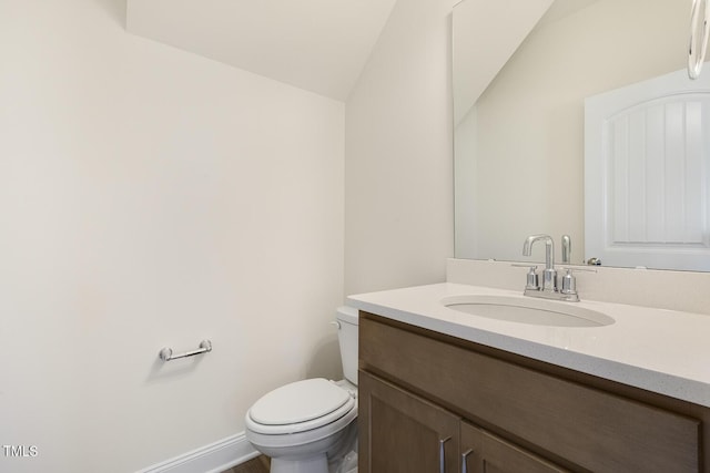 bathroom featuring toilet, vanity, and vaulted ceiling