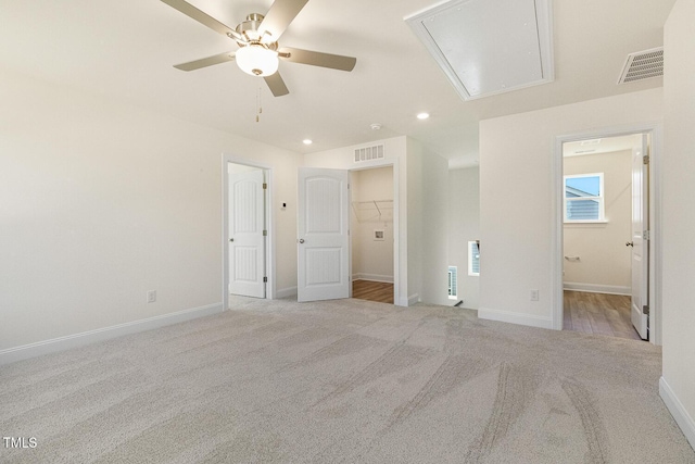 unfurnished bedroom with ceiling fan, a closet, light carpet, and a spacious closet