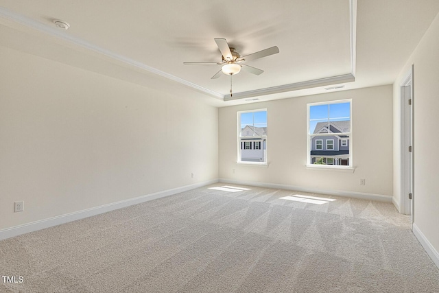 spare room with a raised ceiling, crown molding, ceiling fan, and light colored carpet