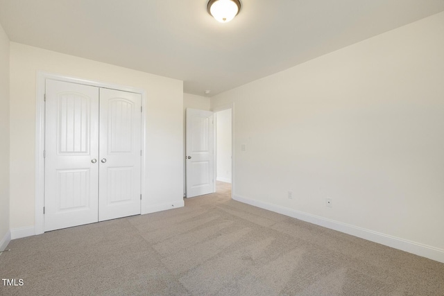 unfurnished bedroom featuring light carpet and a closet