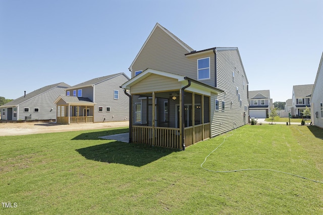 rear view of house featuring a yard and a sunroom