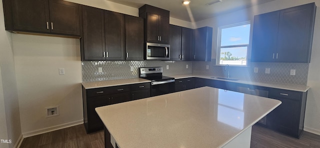 kitchen with dark wood-style floors, a center island, stainless steel appliances, visible vents, and a sink