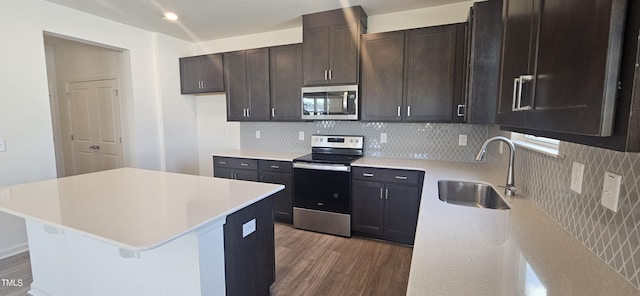 kitchen with light wood finished floors, tasteful backsplash, appliances with stainless steel finishes, light countertops, and a sink