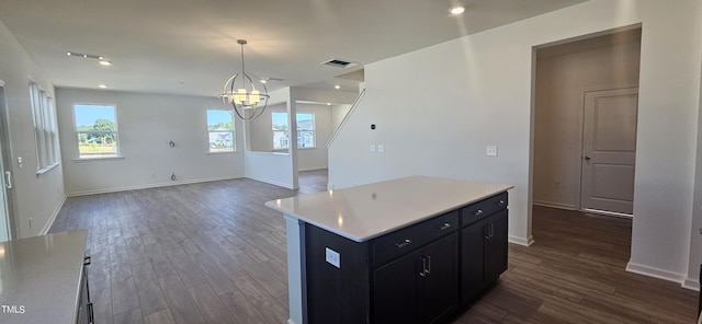 kitchen featuring a center island, light countertops, visible vents, dark wood-type flooring, and dark cabinetry