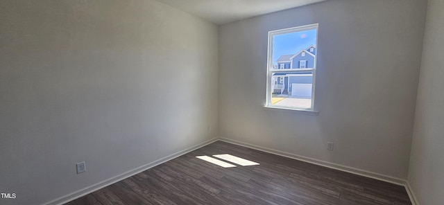 empty room featuring dark wood-type flooring and baseboards