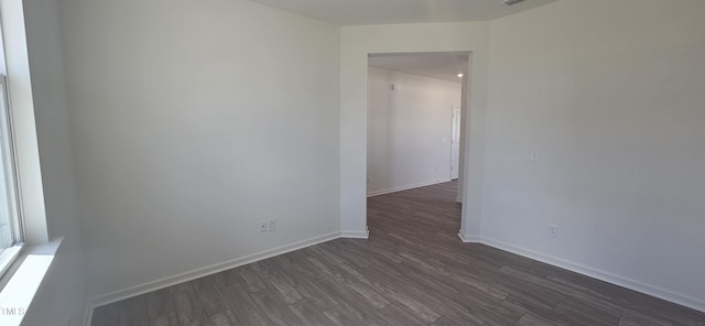 unfurnished room featuring dark wood-style floors, visible vents, and baseboards