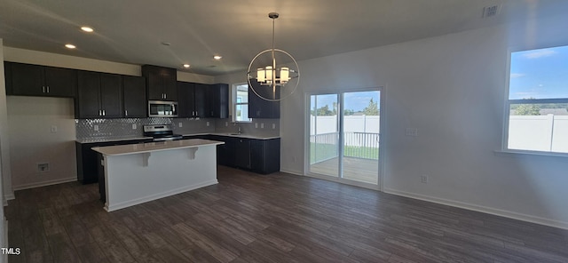 kitchen with stainless steel appliances, a sink, dark cabinets, and tasteful backsplash