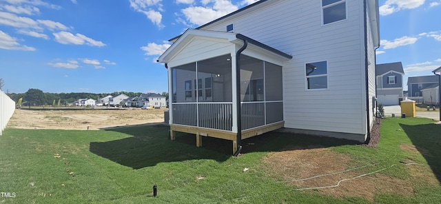 rear view of house with a sunroom, a residential view, and a lawn