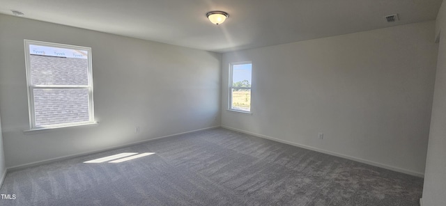 empty room with carpet floors, visible vents, and baseboards