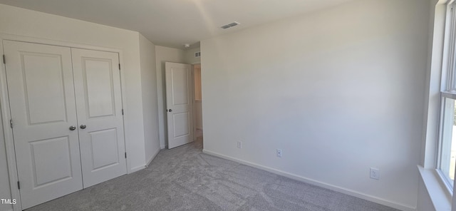 unfurnished bedroom with light carpet, baseboards, visible vents, and a closet