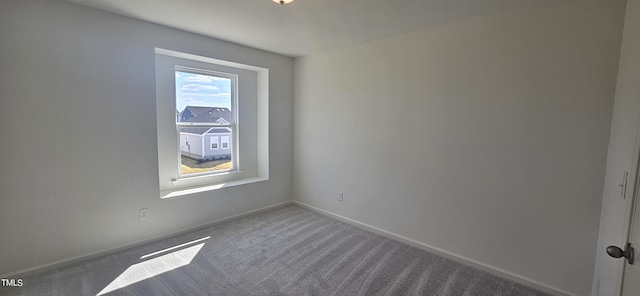 carpeted spare room featuring baseboards