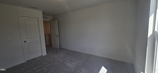 unfurnished bedroom with baseboards, visible vents, and dark carpet