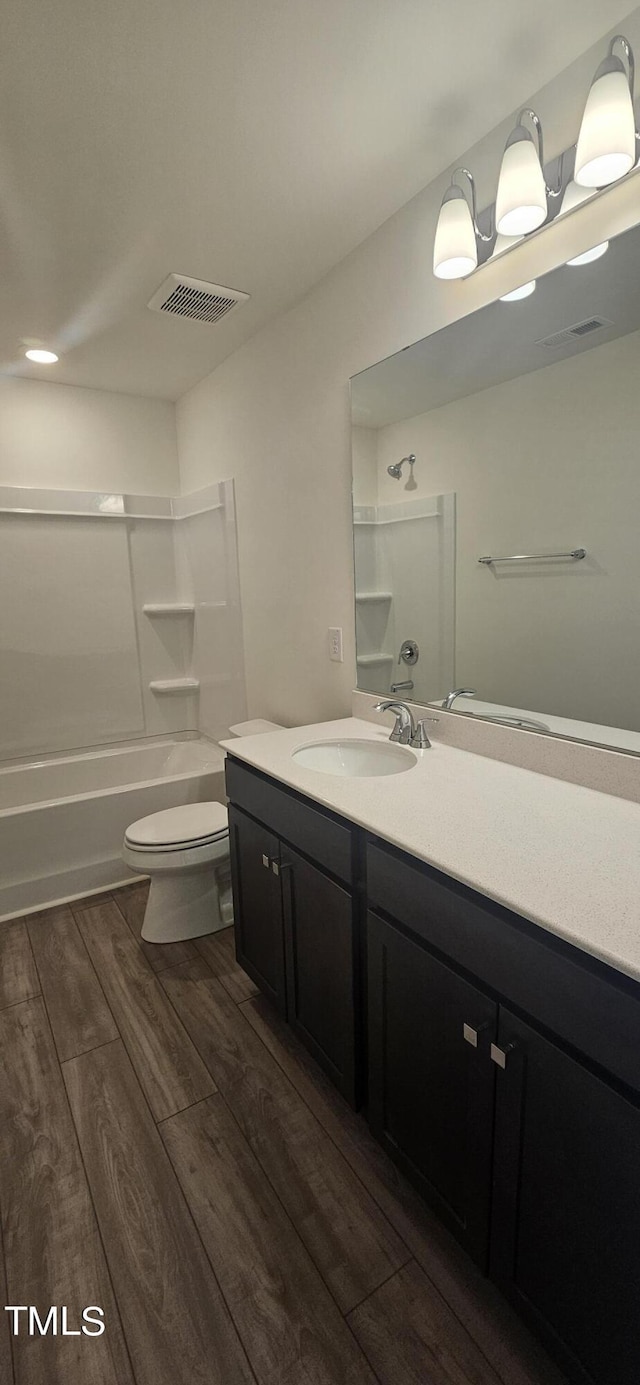 bathroom with visible vents, toilet, vanity, shower / tub combination, and wood finished floors