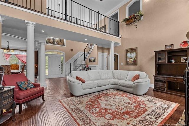 living room with a high ceiling, decorative columns, and dark wood-type flooring