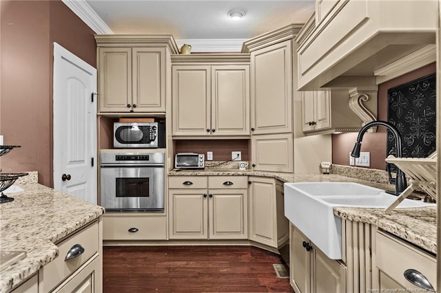 kitchen featuring cream cabinets, appliances with stainless steel finishes, dark hardwood / wood-style flooring, and light stone counters