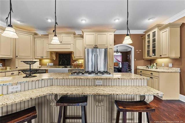 kitchen with a kitchen bar, hanging light fixtures, stainless steel appliances, and dark wood-type flooring