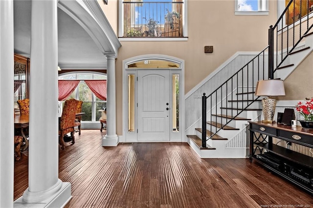 entryway featuring dark hardwood / wood-style flooring, decorative columns, and a towering ceiling