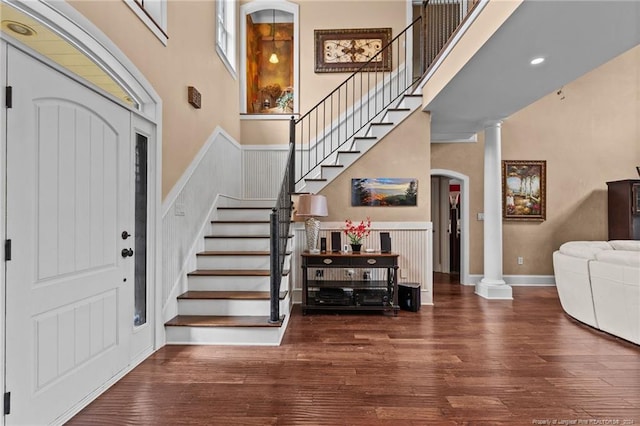 entrance foyer with dark wood-type flooring, ornate columns, and a high ceiling