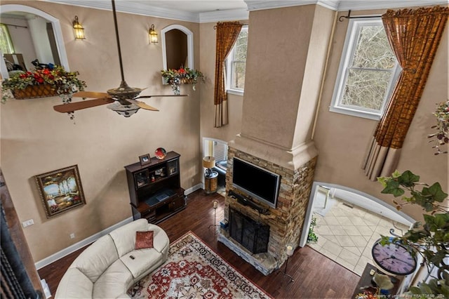 living room featuring ceiling fan, crown molding, a fireplace, and dark hardwood / wood-style floors