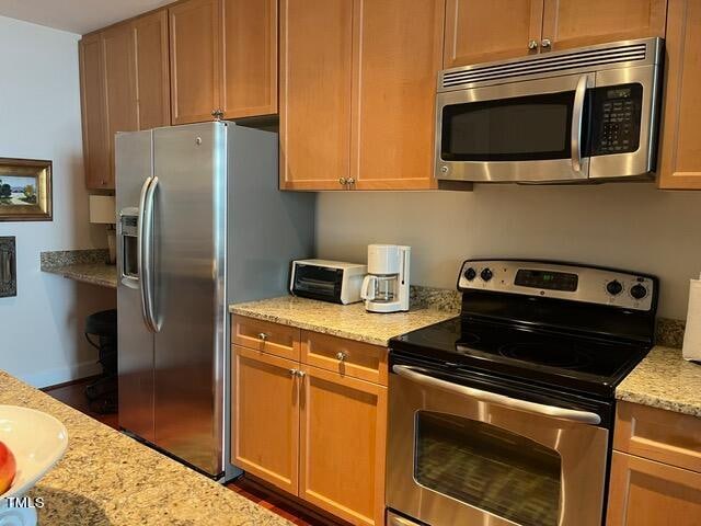 kitchen with appliances with stainless steel finishes and light stone counters