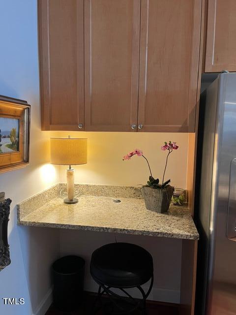 kitchen with a kitchen breakfast bar, stainless steel refrigerator, and light stone counters