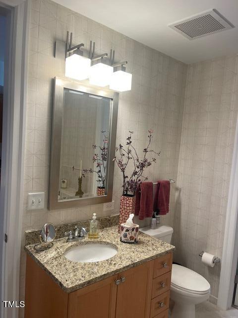 bathroom featuring tile walls, toilet, tasteful backsplash, and vanity