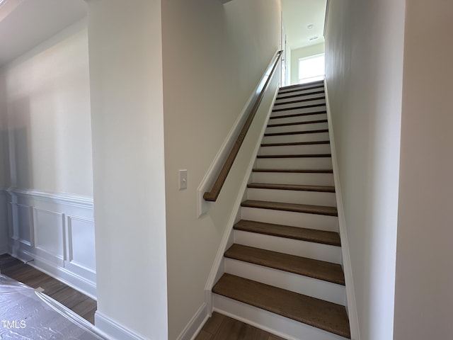 stairs with a decorative wall and wood finished floors