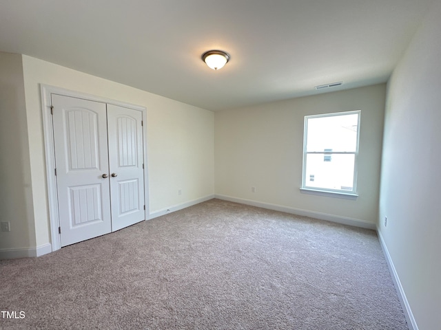 unfurnished bedroom with baseboards, carpet, visible vents, and a closet