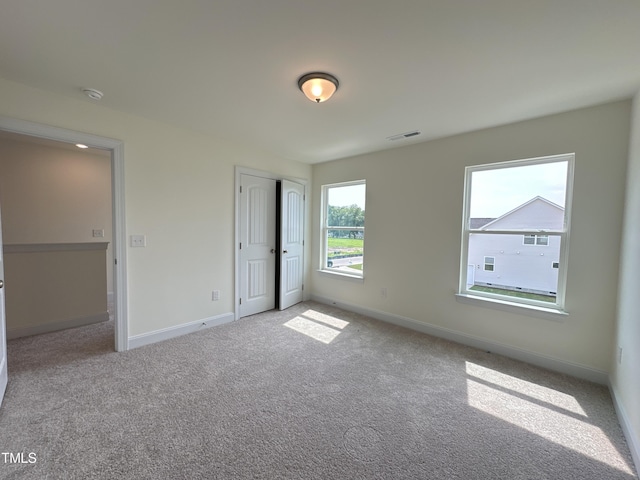 unfurnished bedroom with a closet, carpet flooring, visible vents, and baseboards