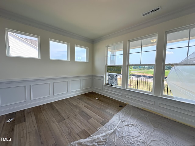 spare room featuring dark wood-type flooring, plenty of natural light, visible vents, and crown molding