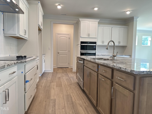 kitchen with white cabinets, black electric cooktop, crown molding, under cabinet range hood, and a sink