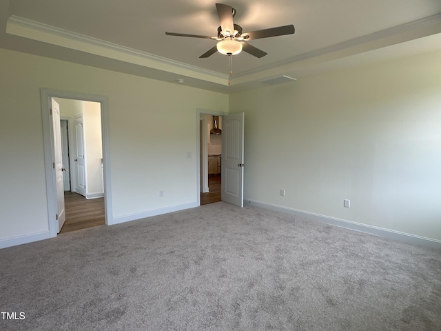 unfurnished bedroom featuring carpet floors, a raised ceiling, ornamental molding, and baseboards