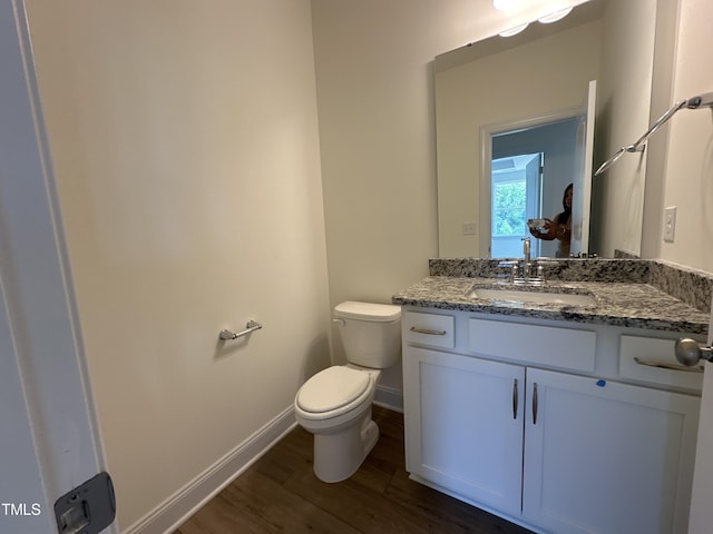 bathroom featuring toilet, baseboards, wood finished floors, and vanity