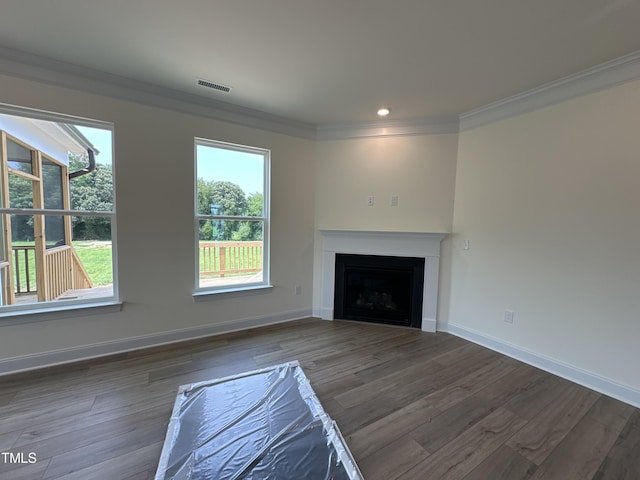 unfurnished living room with a healthy amount of sunlight, wood finished floors, visible vents, and crown molding