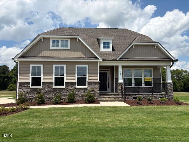 103 Sage Ln Lot 009, Four Oaks, NC 27524 - craftsman-style home with a front yard, covered porch, stone siding, a shingled roof, and board and batten siding