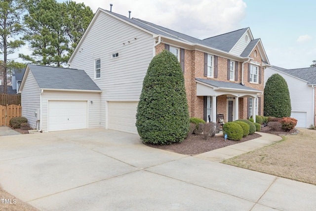 view of side of property with covered porch, fence, brick siding, and driveway