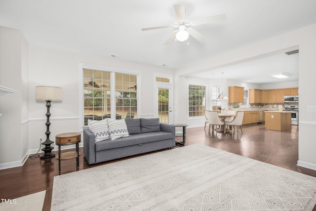 living room with dark wood finished floors, baseboards, visible vents, and ceiling fan